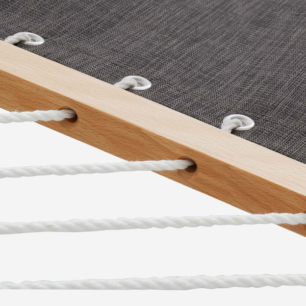 Close-up of a wooden hammock frame with white ropes on a dark fabric background