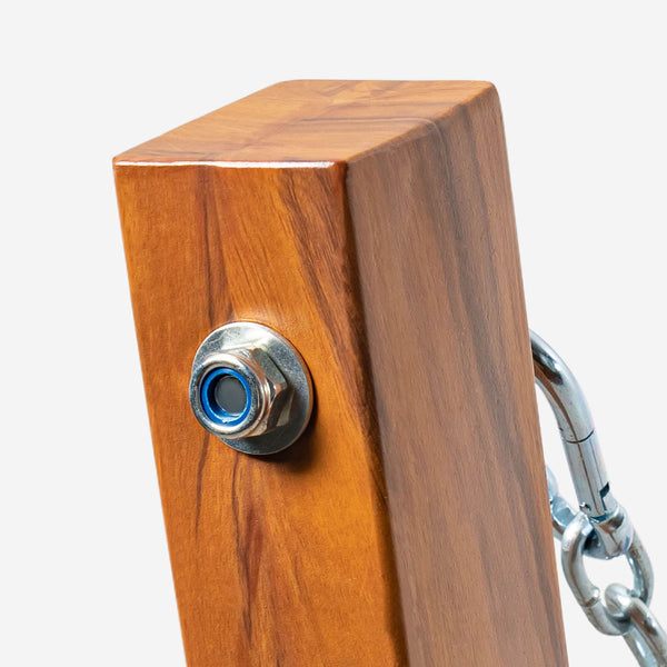 Wooden block with metal button and chain on a white background
