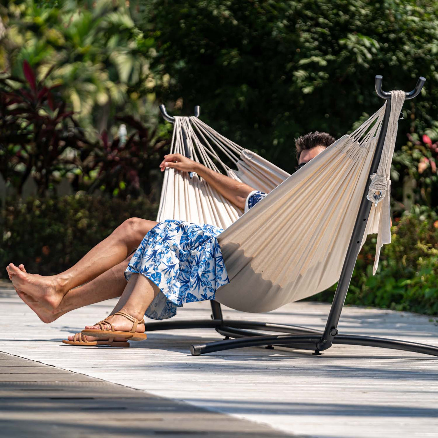 A couple enjoys lounging on the Lazy Daze Brazilian Premium Polycotton Hammock in a backyard.#color_natural