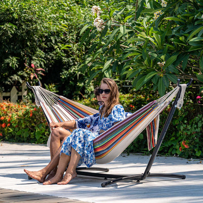 A couple lounging on Lazy Daze Brazilian Premium Polycotton Hammock in a backyard setting.#color_tan-stripes