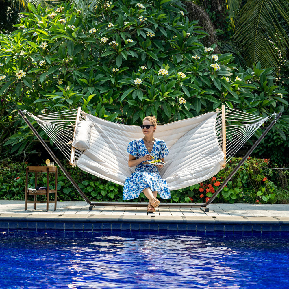 Woman relaxing in Lazy Daze Cotton Rope Hammock Combo in a backyard setting.#color_beige