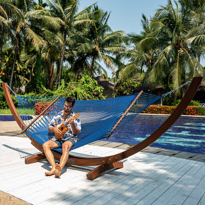 Person relaxing on Lazy Daze Double Caribbean Rope Hammock in Blue by the poolside.#color_blue