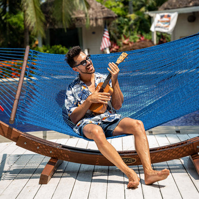 Person lounging in Lazy Daze Double Caribbean Rope Hammock in Blue in the backyard.#color_blue