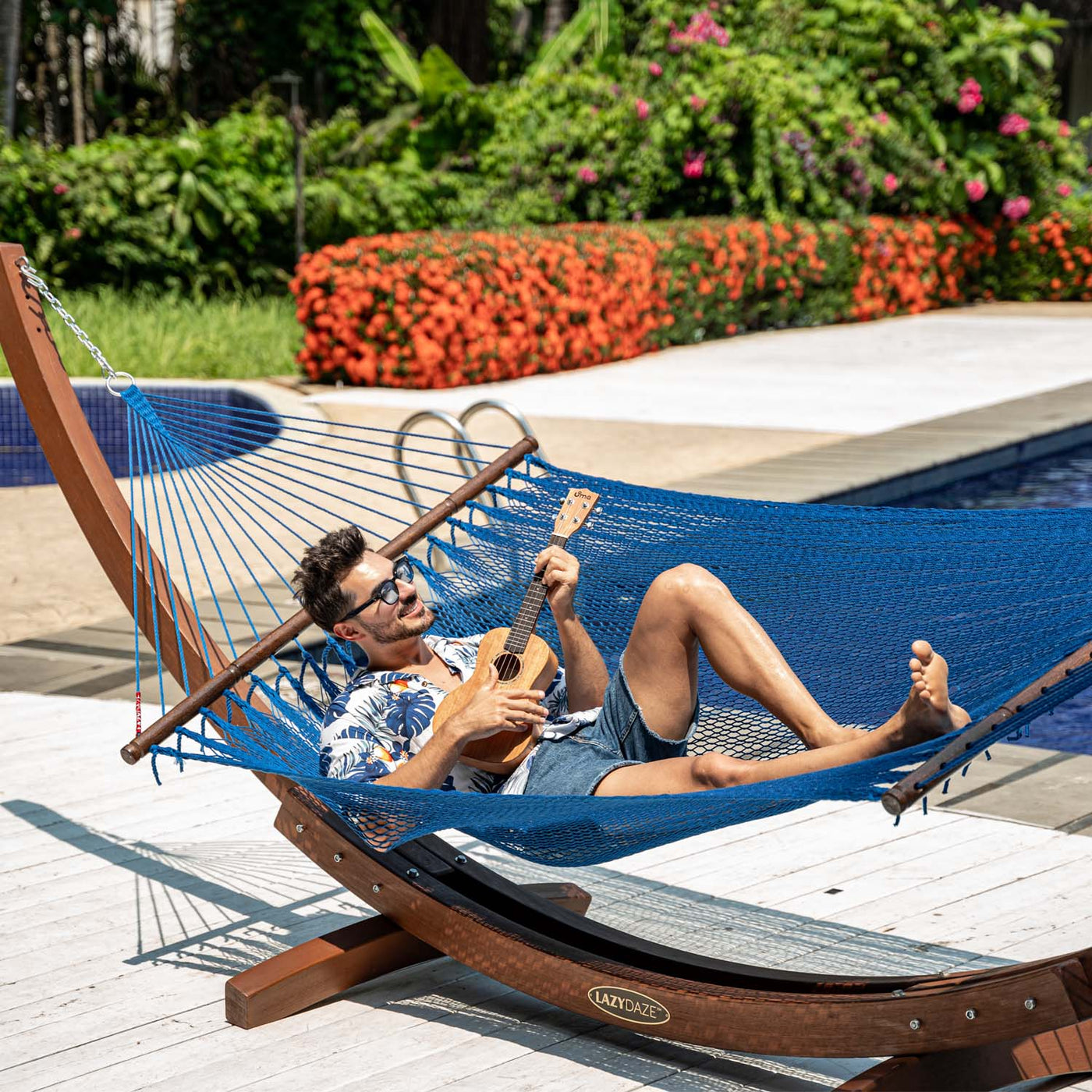 Lazy Daze Double Caribbean Rope Hammock in Blue with person relaxing by the pool.#color_blue