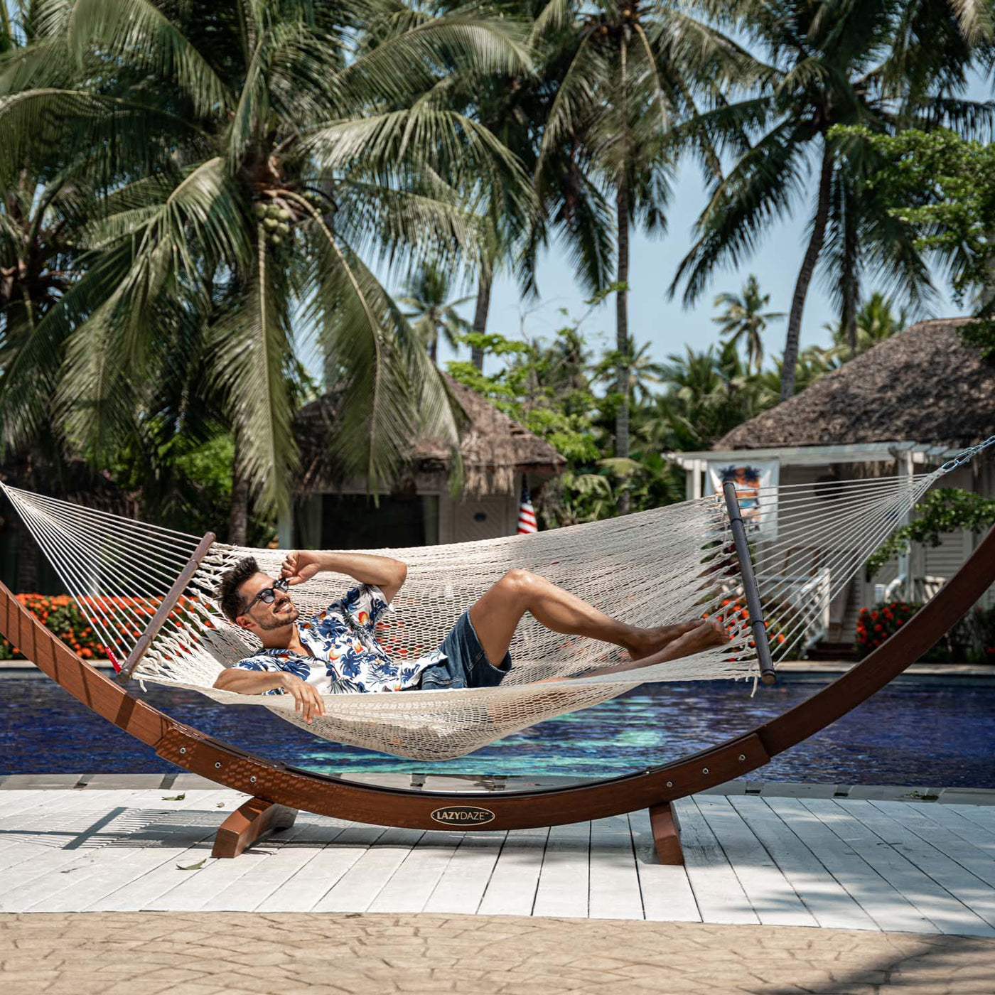 Person relaxing on Lazy Daze Double Caribbean Rope Hammock in Cream by the poolside.#color_gream