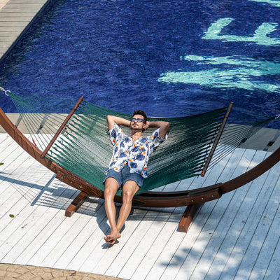 Enjoying a peaceful moment in the Lazy Daze Double Caribbean Rope Hammock in Green by the pool.#color_green