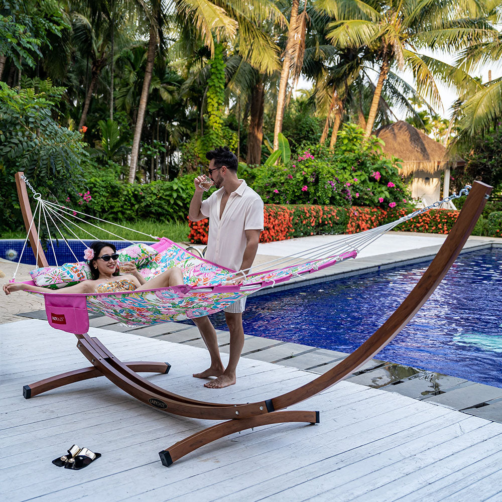 Couple relaxing on Lazy Daze Double Hammock with Curved Spreader Bar in Illy, set by the backyard pool.#color_illy