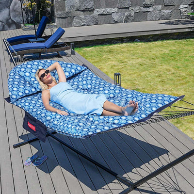 A woman enjoying the Lazy Daze Double Hammock with Curved Spreader Bar in navy in a sunny backyard.#color_navy