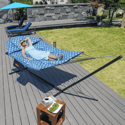 A woman relaxing on the Lazy Daze Double Hammock with Curved Spreader Bar in navy, set up in a backyard.#color_navy