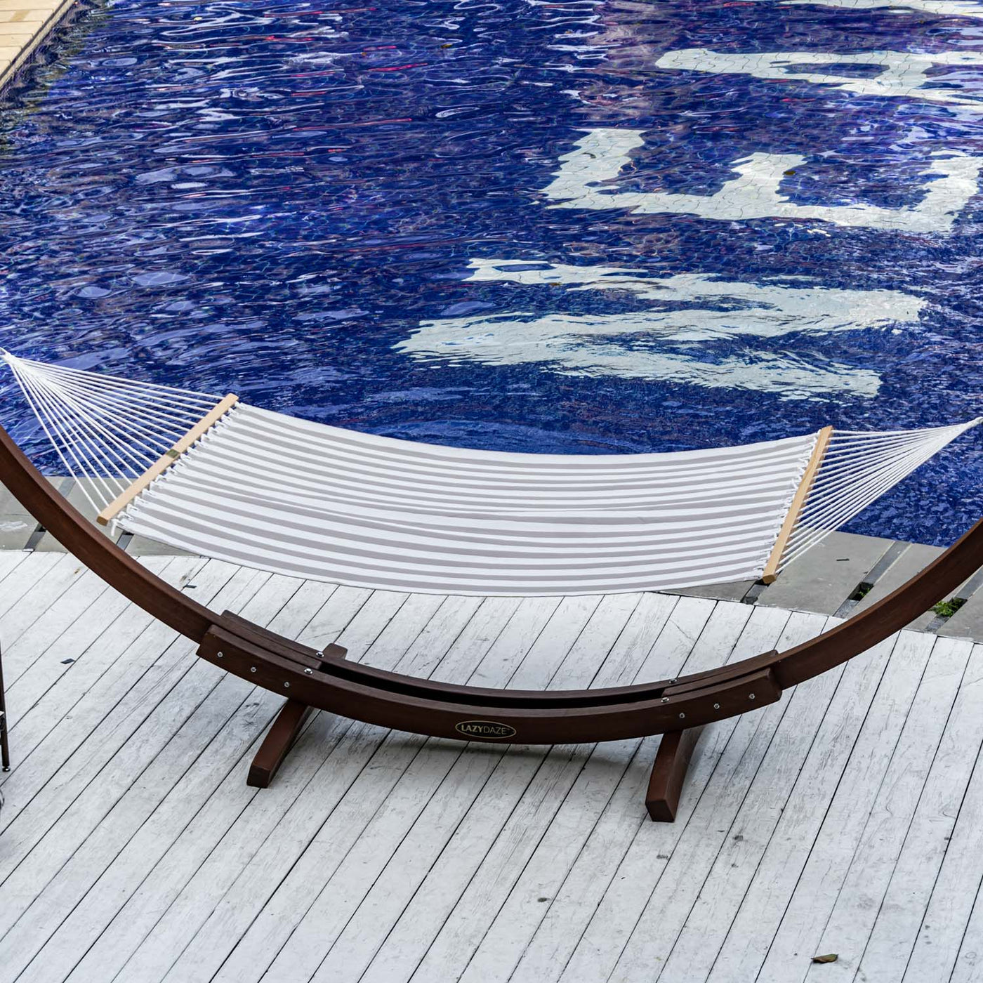 Lazy Daze Double Poolside Hammock in Beige White Stripes set up by the poolside.#color_beige-white-stripes