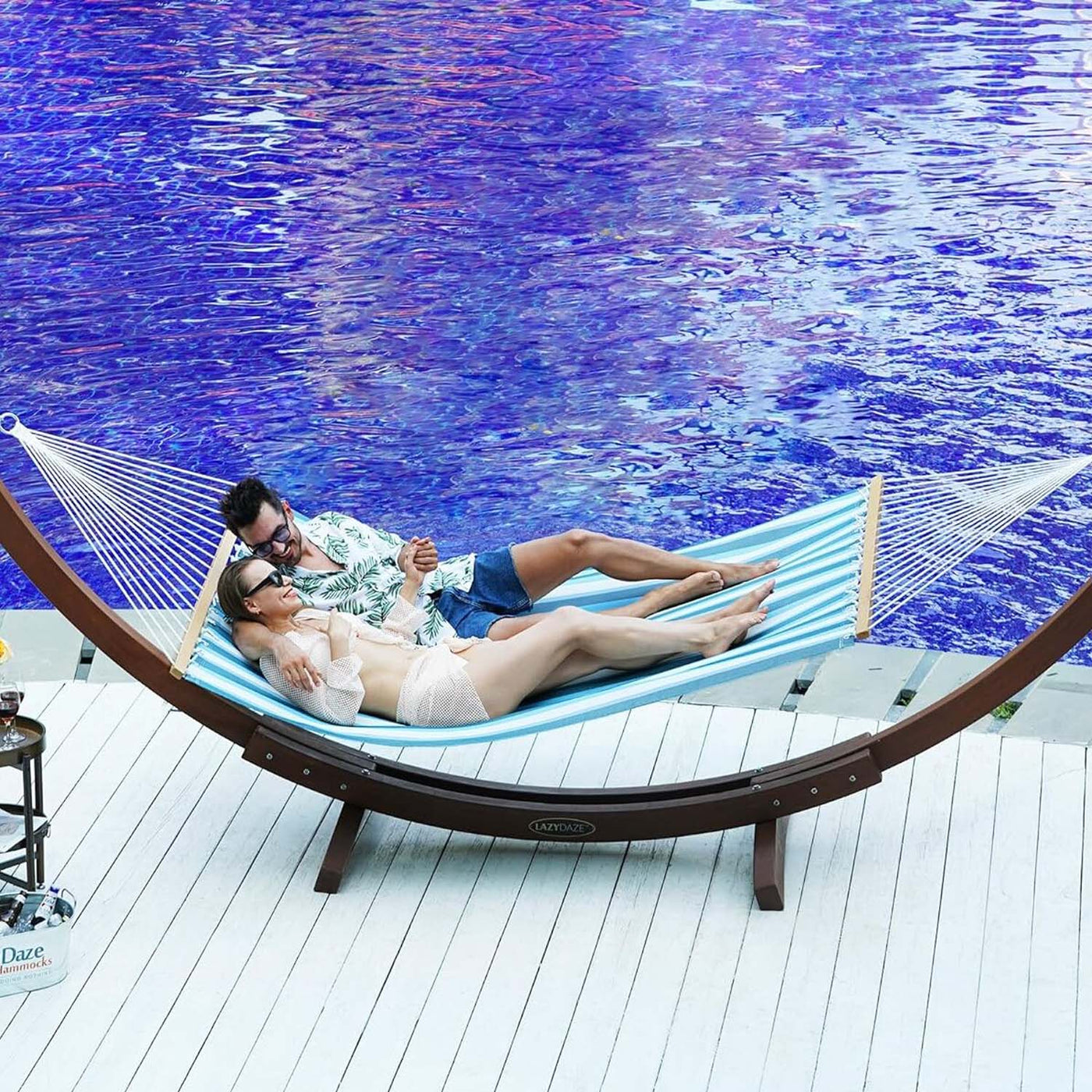 Couple unwinding on the Lazy Daze Double Poolside Hammock in Blue White Stripes by the poolside.#color_blue-white-stripes