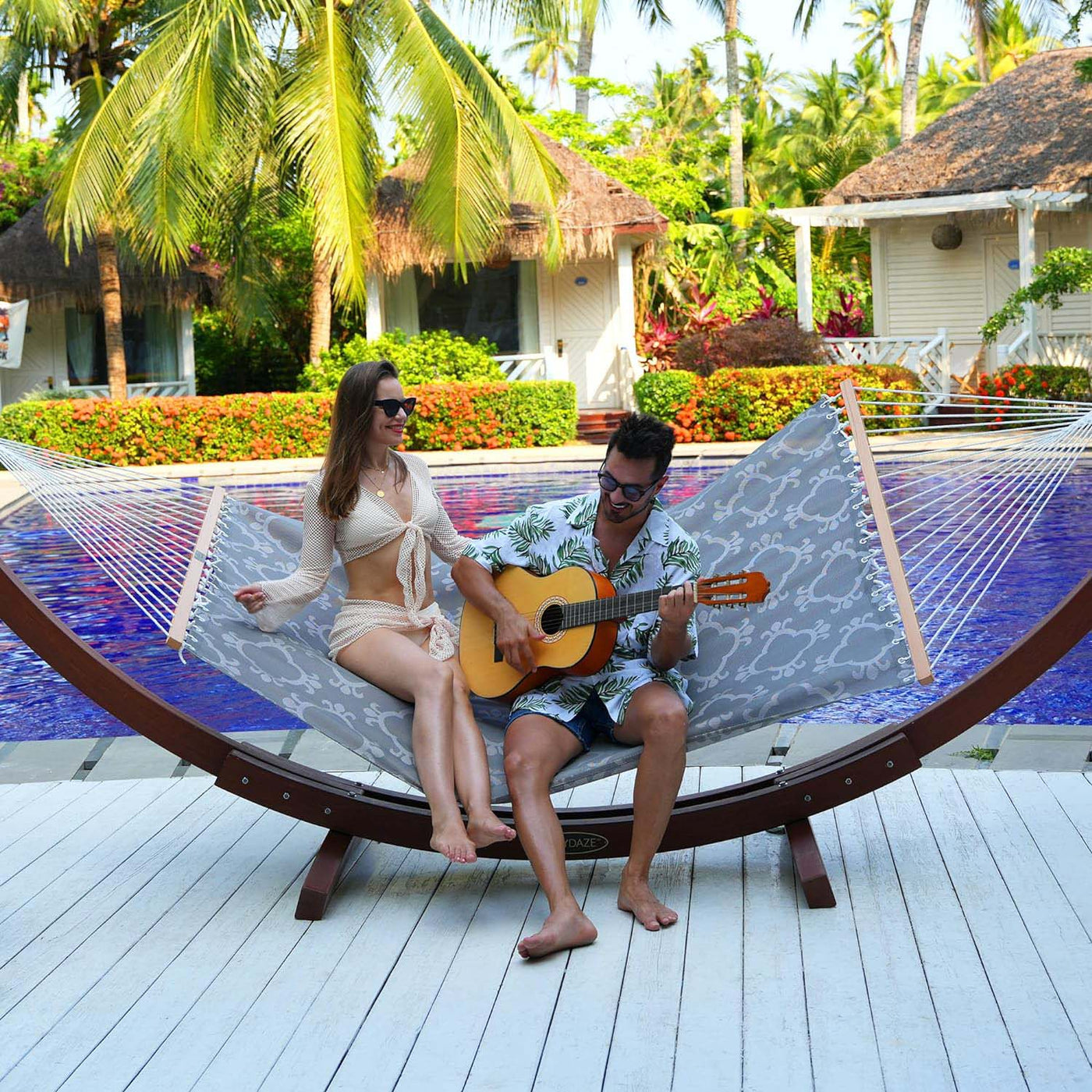 Couple unwinding on the Lazy Daze Double Poolside Hammock in Four Leaf Clover, playing the guitar.#color_four-leaf-clover