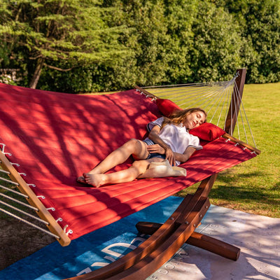 Lazy Daze double quilted hammock set on a bright lawn, featuring a woman enjoying a peaceful moment.#color_burgundy