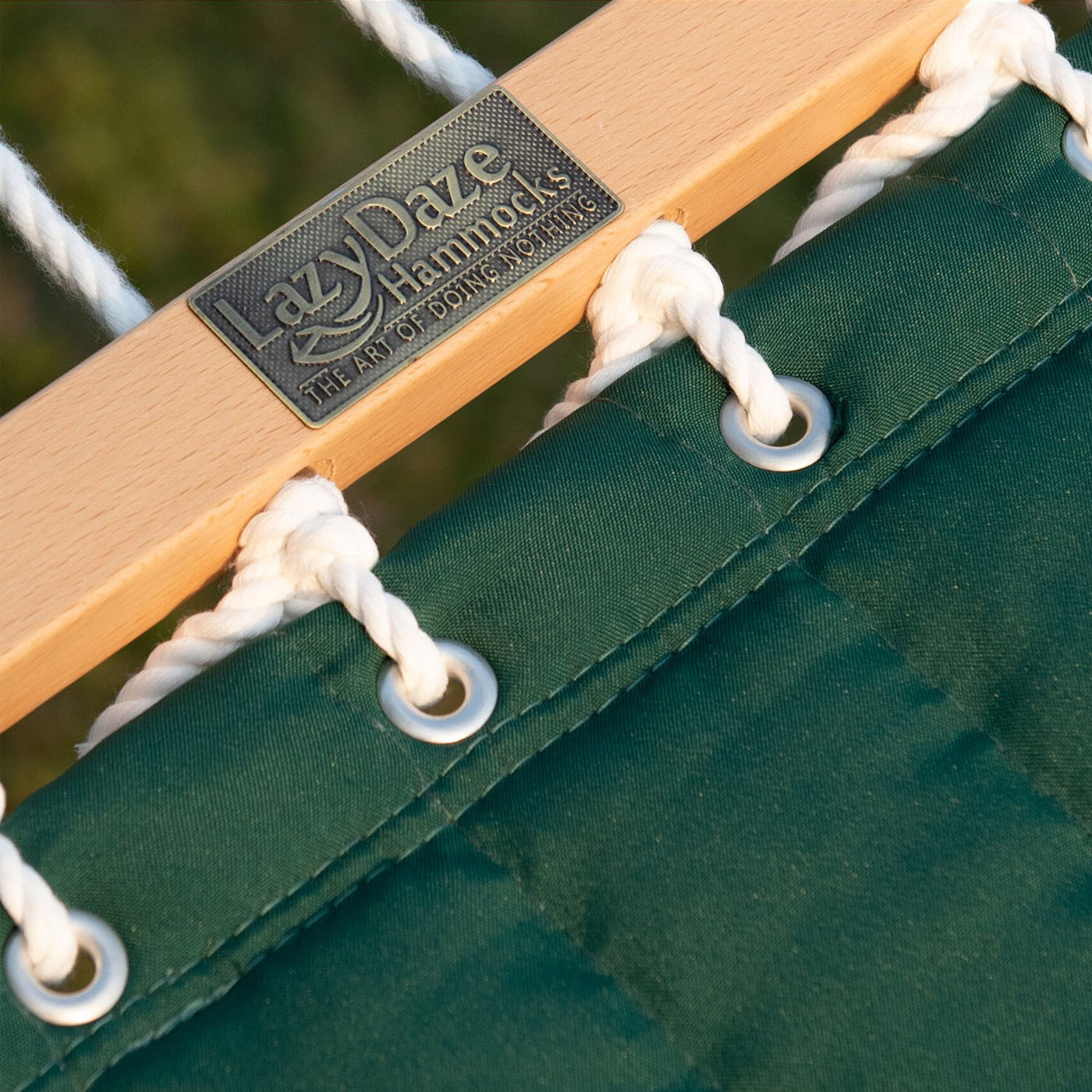 Detailed view of the hardwood spreader bar on the Lazy Daze double quilted hammock in dark green.#color_dark-green