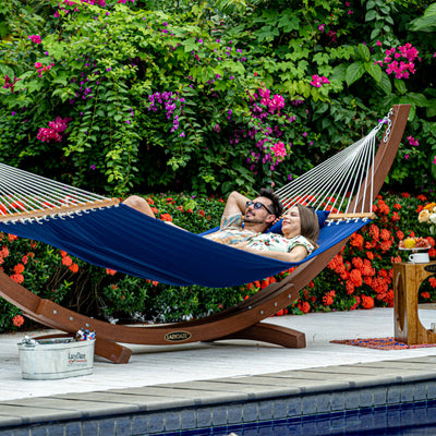 A man and woman relaxing on a Lazy Daze Large Double Quilted Hammock in Dark Blue in the backyard.#color_dark-blue