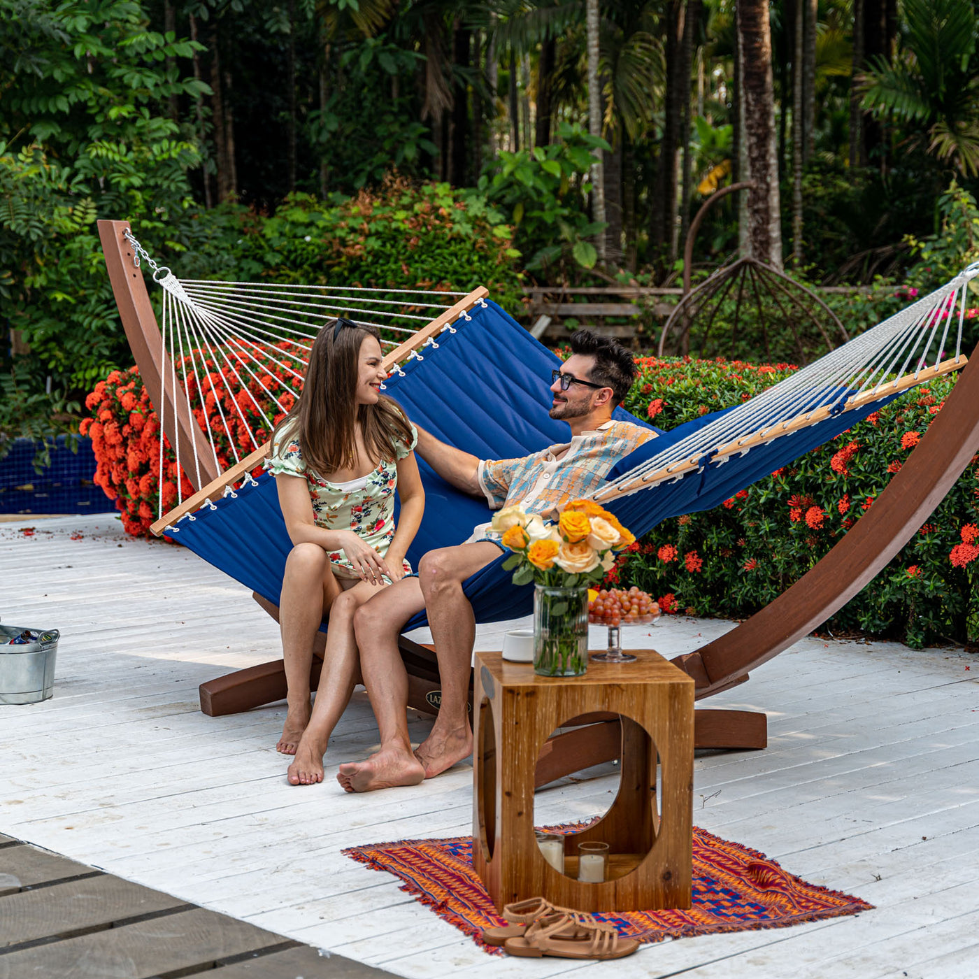 A man and woman lounging on a Lazy Daze Large Double Quilted Hammock in Dark Blue in the backyard.#color_dark-blue