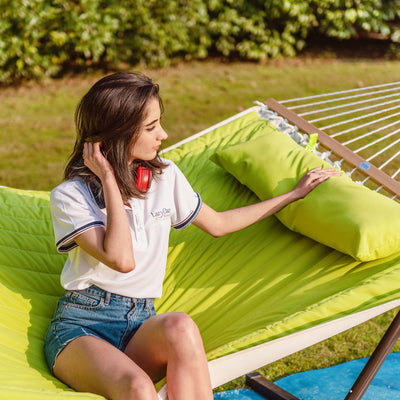 Lazy Daze large double quilted hammock in lemon green, one woman enjoying the sun on a grassy lawn.#color_lemon-green