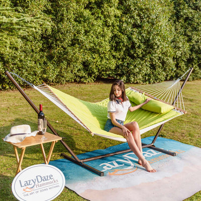 Lazy Daze large double quilted hammock in lemon green, one woman relaxing outdoors on a sunny grassy lawn.#color_lemon-green