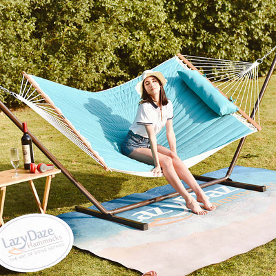 Lazy Daze large double quilted hammock in sky blue, one woman relaxing under the sun on a grassy lawn.#color_sky-blue