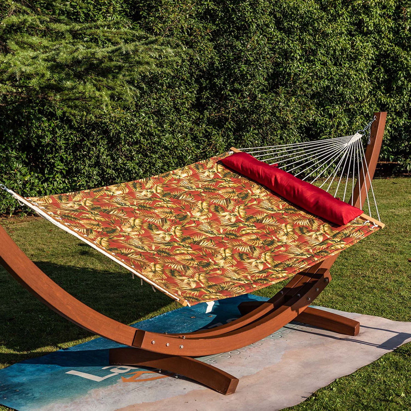 Lazy Daze large double reversible quilted hammock with red floral design, placed on grass for relaxation.#color_floral-red