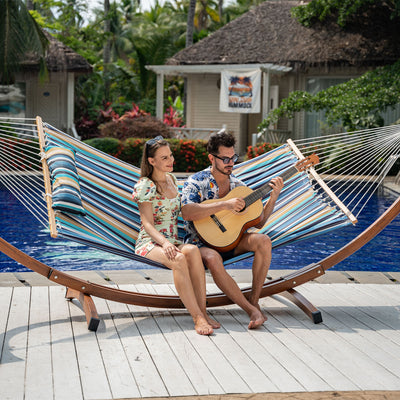 A couple relaxing on the Lazy Daze Large Double Stripes Quilted Hammock in a backyard.#color_beaches-stripes