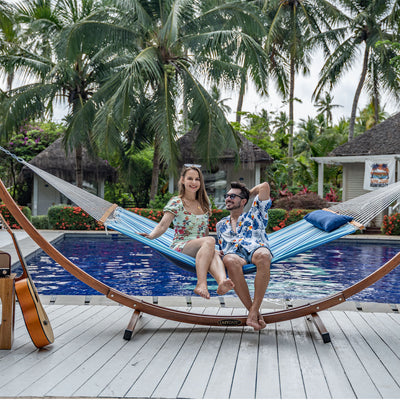 Lazy Daze Large Double Stripes Quilted Hammock in Blue Stripes, backyard scene with a couple relaxing.#color_blue-stripes