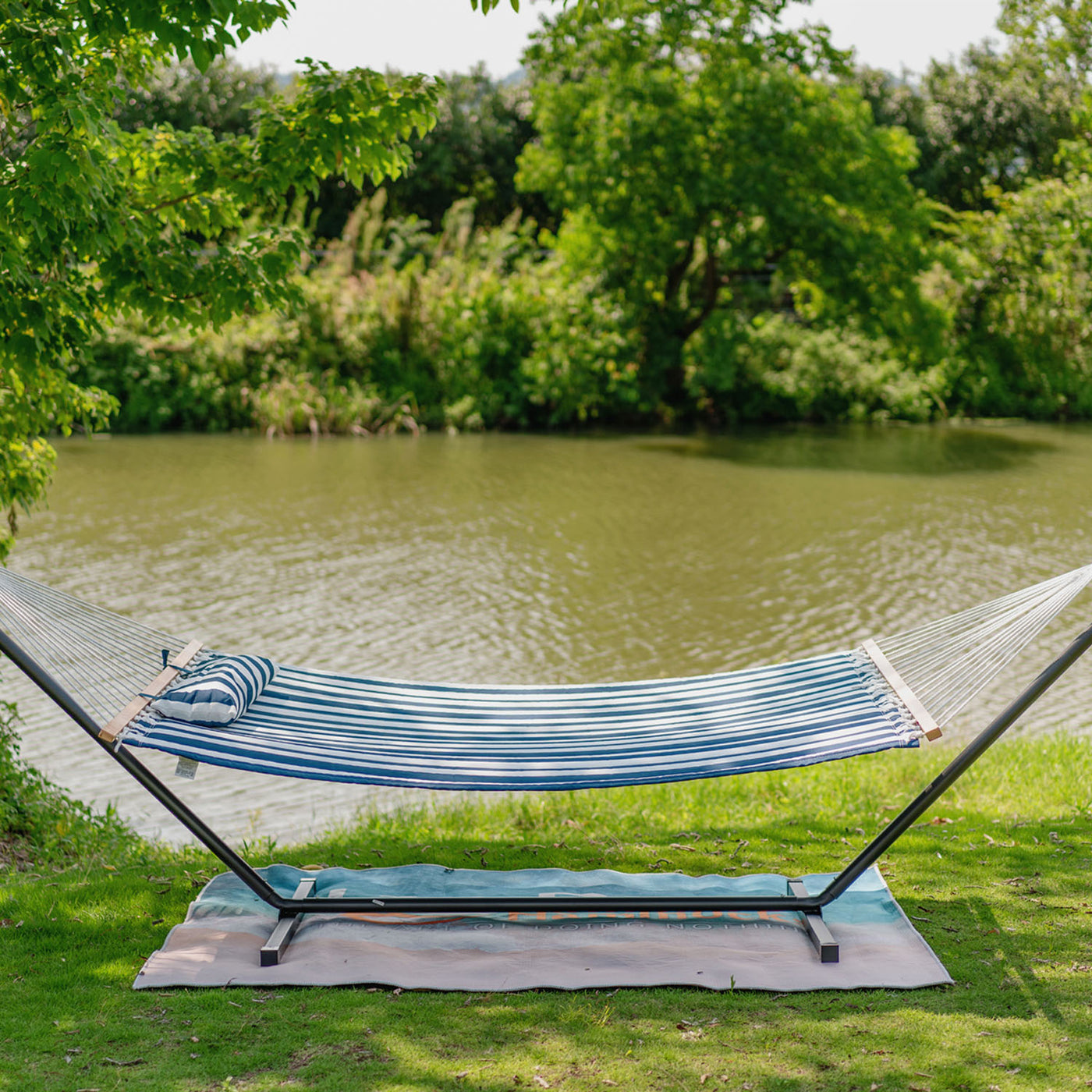 Blue White Stripes Lazy Daze hammock set up on grassy outdoor space for relaxation.#color_blue-white-stripes