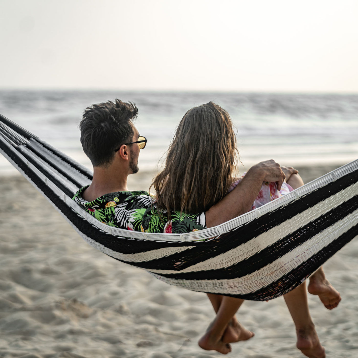 Lazy Daze Mayan Family Hammock with a couple enjoying the beach view.#color_black-and-white-stripes