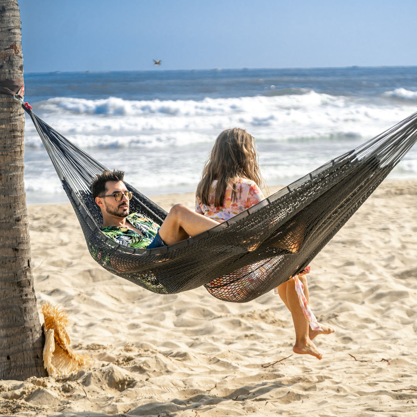 Gray Lazy Daze Mayan Family Hammock with a couple enjoying ocean views on a sunny day.#color_gray