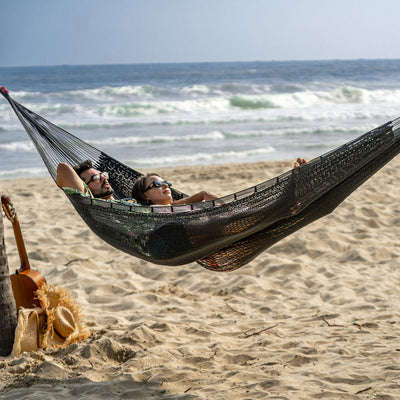 Lazy Daze Mayan Family Hammock in gray with a couple lounging near the sea on the beach.#color_gray