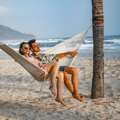 A couple enjoying the Lazy Daze Mayan Family Hammock in white at a beach.#color_white