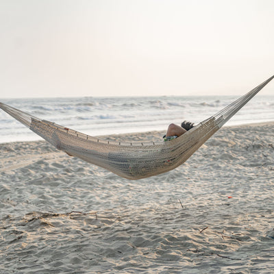 Lazy Daze Mayan Family Hammock in white color with a man relaxing on the beach.#color_white