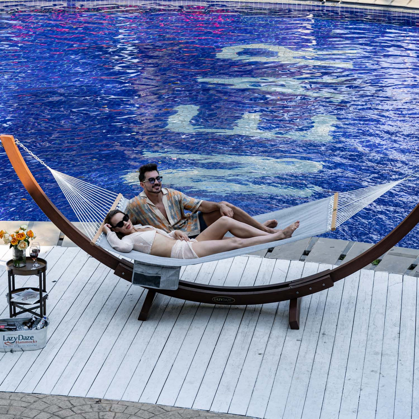 Couple relaxing on the Lazy Daze Quick Dry Hammock in Gray by the poolside.#color_gray