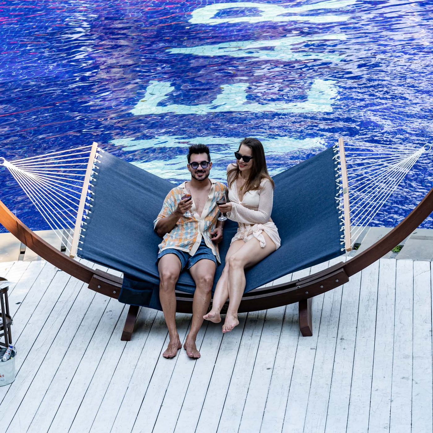 Couple relaxing on the Lazy Daze Quick Dry Hammock in Navy Blue by the poolside.#color_navy-blue