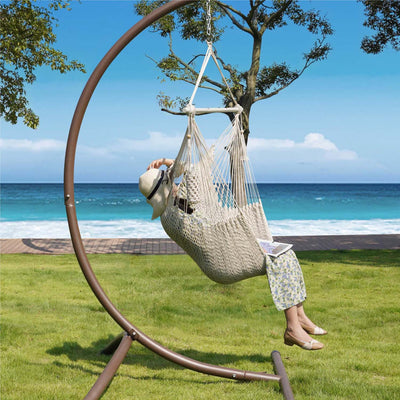 A woman relaxing in Lazy Daze beige rope swing chair.#color_beige