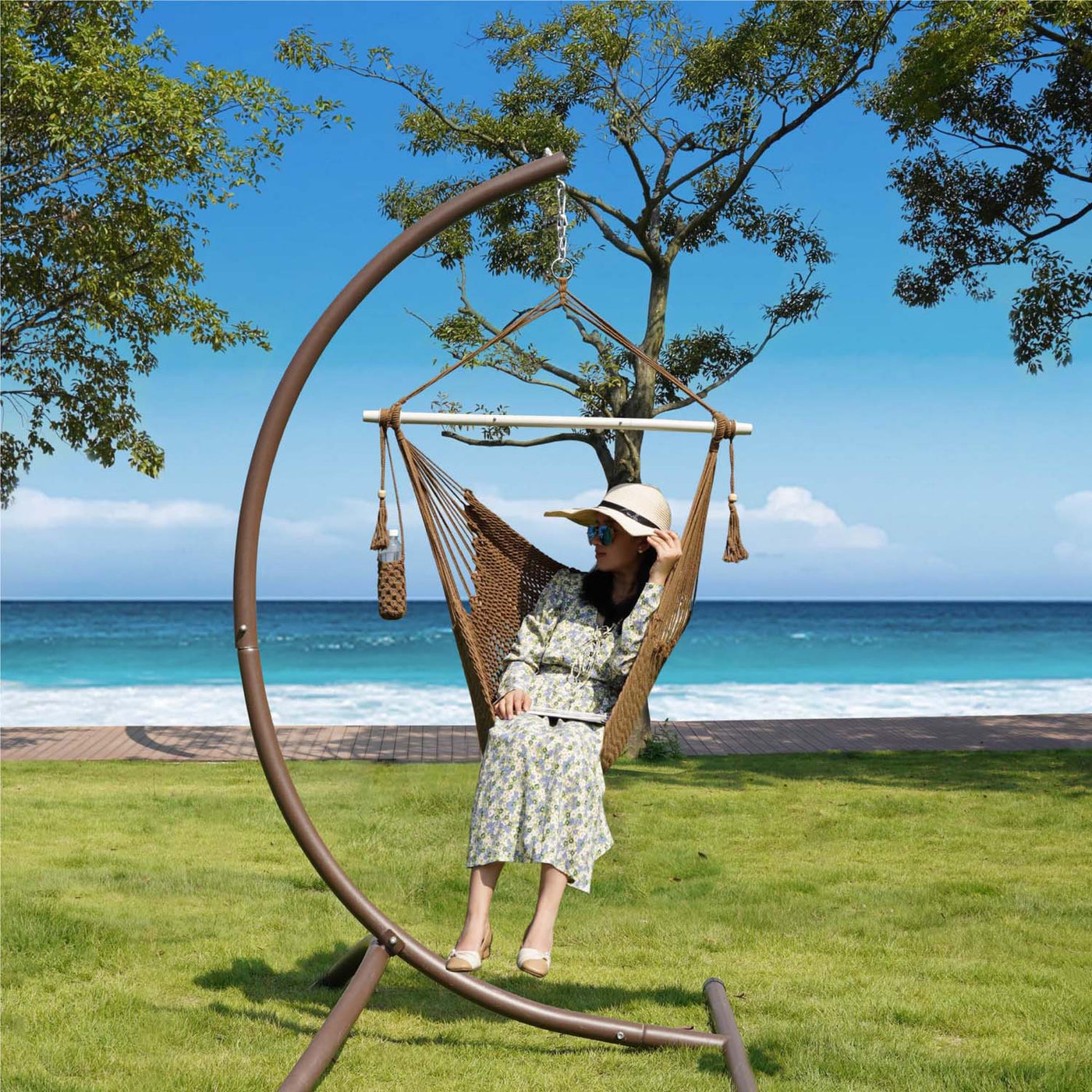 A woman relaxing in Lazy Daze tan rope swing chair outdoors.#color_tan