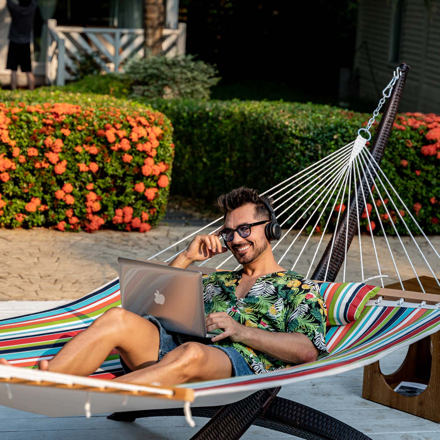 A man relaxing on the Lazy Daze Sunbrella Double Quilted Hammock in the backyard.#color_carousel-confetti