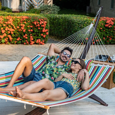 A couple lounging on the Lazy Daze Sunbrella Double Quilted Hammock in their backyard.#color_carousel-confetti