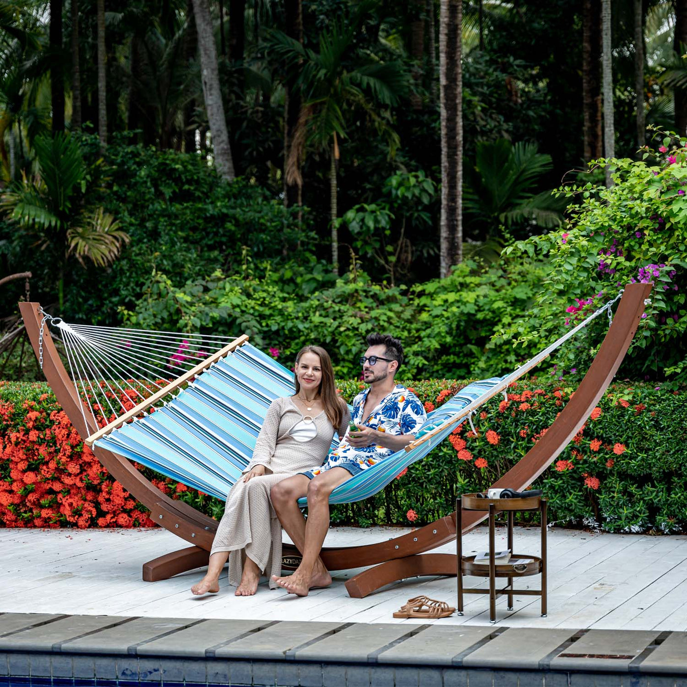 A couple enjoying the Lazy Daze Sunbrella Single-layer Hammock in Gateway Mist in a garden.#color_gateway-mist