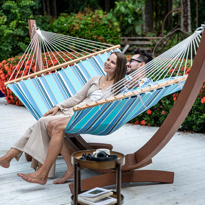 Couple unwind in Lazy Daze Sunbrella Single-layer Hammock in Gateway Mist, in their backyard garden.#color_gateway-mist