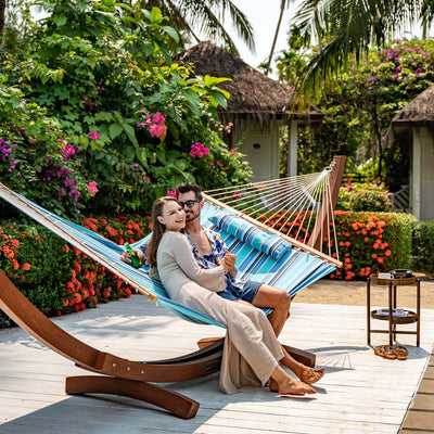 Relaxing couple in Lazy Daze Sunbrella Single-layer Hammock, amidst lush garden greenery.#color_gateway-mist