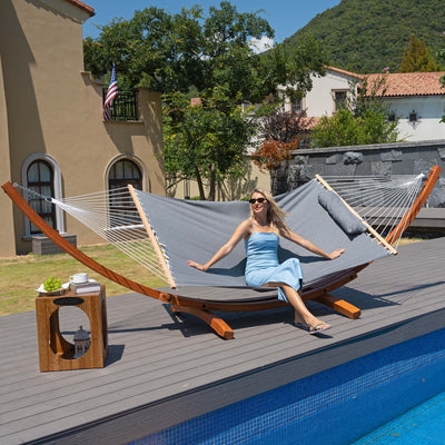 A woman unwinding in the Lazy Daze Sunbrella Single-layer Hammock in Gray, placed in a relaxing backyard.#color_gray