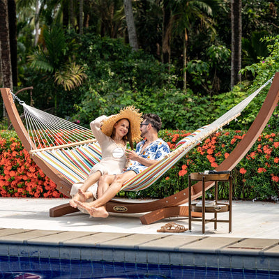 A man and woman enjoying the Lazy Daze Sunbrella Single-layer Hammock in orange, in a serene backyard.#color_orange