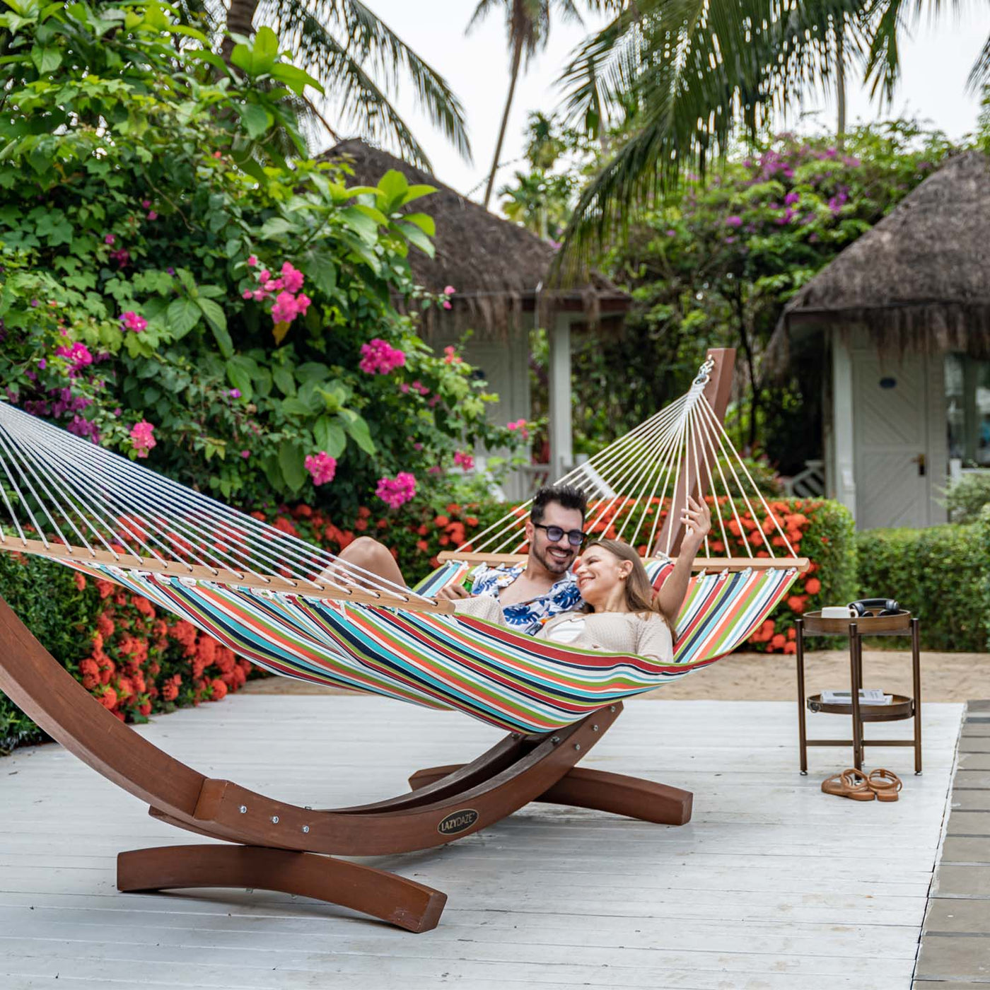 Couple unwinding together in Lazy Daze Sunbrella Single-layer Hammock in orange, set in a garden.#color_orange