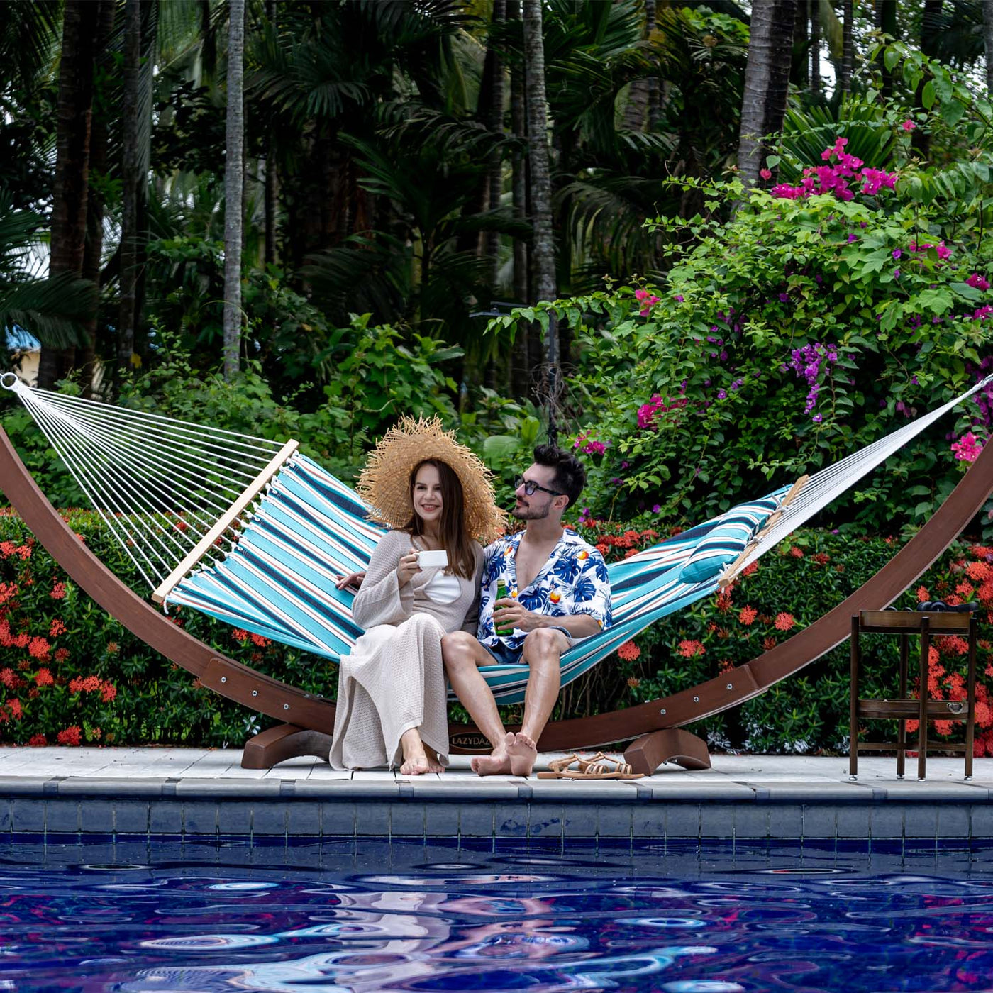 A couple relaxing on the Lazy Daze Sunbrella Single-layer Hammock in a peaceful backyard.#color_token-surfside