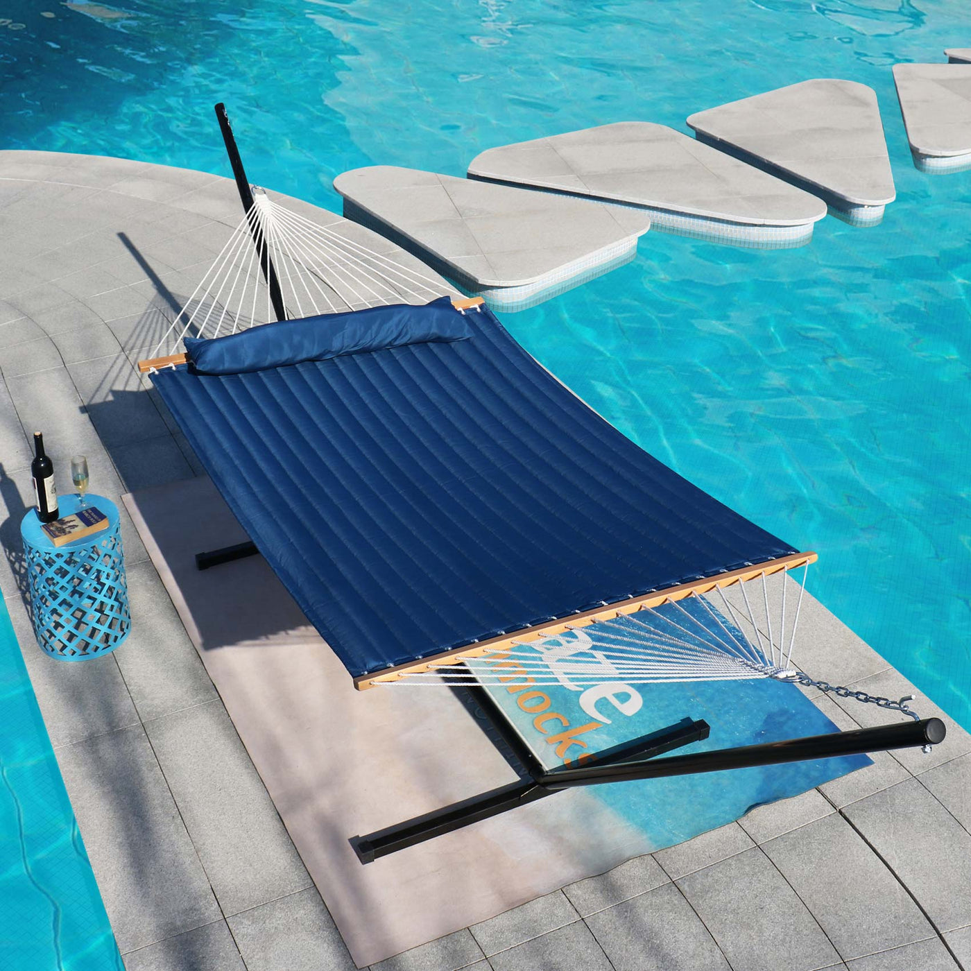 Lazy Daze double quilted hammock in dark blue placed elegantly by a poolside in a serene outdoor setting.#color_dark-blue