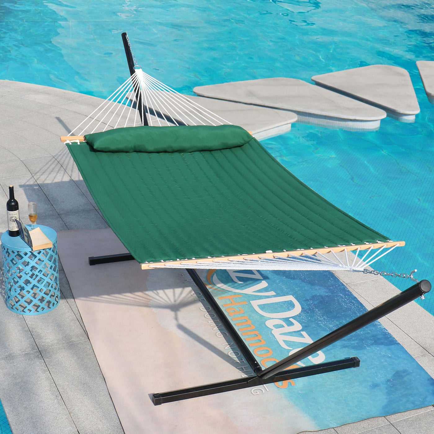 Lazy Daze double quilted hammock in dark green placed elegantly by a poolside in a serene outdoor setting.#color_dark-green